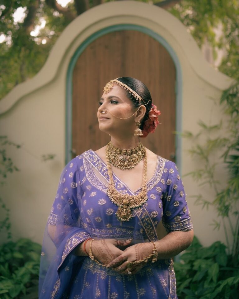 Bride in a purple lehenga walking toward the outdoor mandap at her Gurugram wedding.